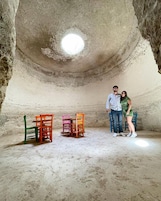 A room with a high ceiling and a small light fixture. There are four chairs in the room.