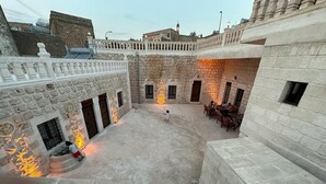 A courtyard with stone walls, a central open space, and a seating area with tables and chairs. - Şikeft Butik Otel (Midyat)