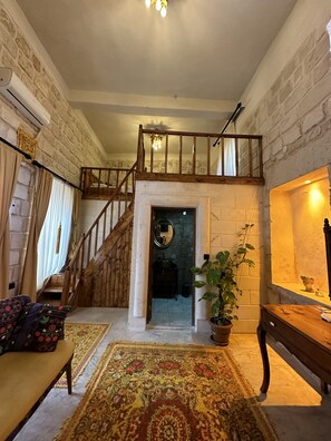 Un vaste espace de vie doté d’un haut plafond, d’un escalier en bois et d’un grand tapis.