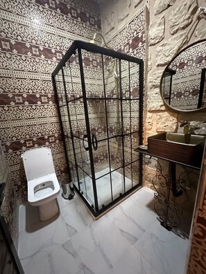 Une salle de bain comprenant des toilettes, un espace douche et un lavabo avec un miroir.