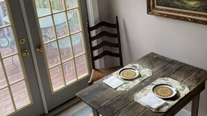 A dining area with a wooden table, two chairs, and a painting on the wall. - Beautiful 4-Bedroom Home • Walk to Beach, Riverwalk & Downtown (Manistee)