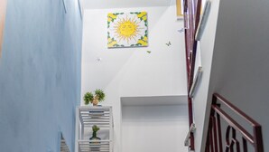 A staircase with blue steps and a red handrail, leading to a landing with a sun-themed artwork. - Angel's Holiday Apartment - Panoramic Relax (San Mauro Castelverde)