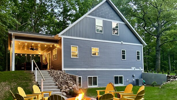 A two-story house with a covered porch and a fire pit in the backyard.