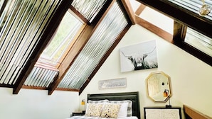 A bedroom with a sloped ceiling, a bed, a nightstand, a dresser, a wall-mounted mirror, and a framed picture. - Charming Loft Cabin - Best Location Davis, Thomas, Canaan Valley. Cold AC (Davis)
