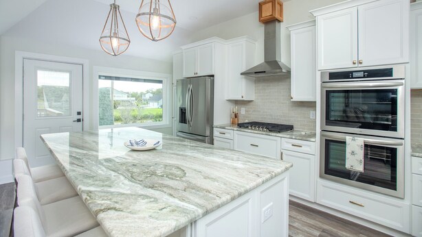 A modern kitchen with white cabinetry, a marble island, stainless steel appliances, and pendant lighting. - Spectacular ocean getaway, vacation done right! (Beaufort)