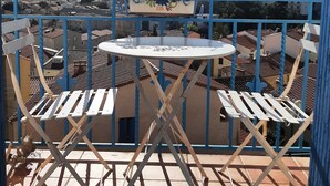 A balcony with a table and chairs, a potted plant, and a view of a town and mountains. - 5mn from the sea studio T1 Banyuls sur mer (Banyuls-sur-Mer)
