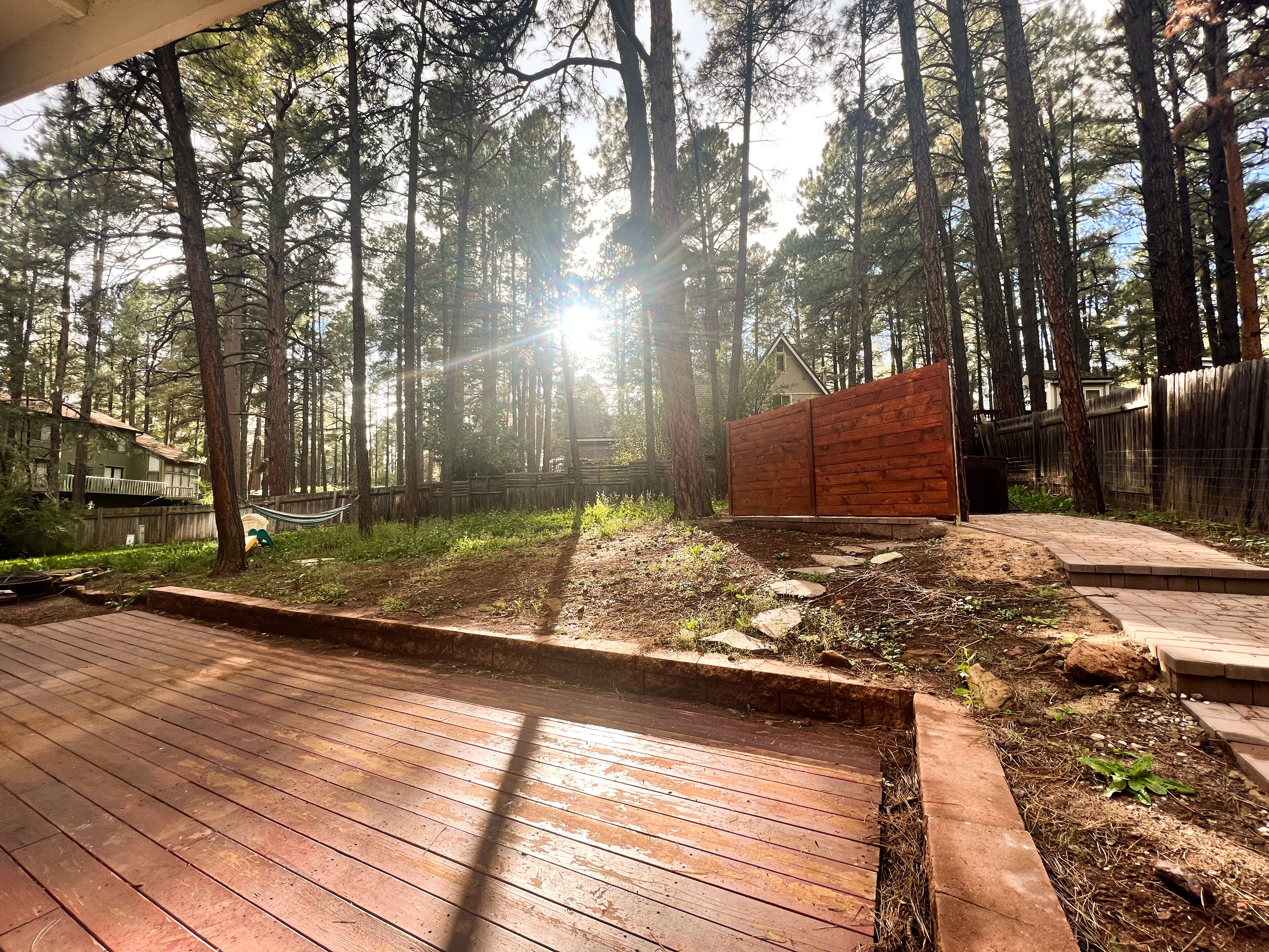 A wooden deck with a stone pathway leading to a wooden fence.