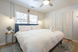 A bedroom with a bed, bedside lamps, a window, and a ceiling fan.