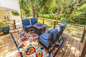 A wooden deck with a table and chairs, surrounded by a colorful rug.