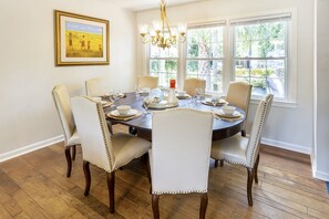 A dining room with a round table, six chairs, and a chandelier.