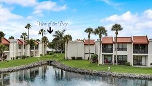 Ein Resort mit Blick auf die Bucht, mit Pool, Springbrunnen, Palmen und modernen Gebäuden mit roten Dächern.