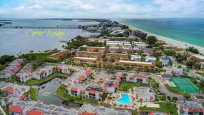 Luftaufnahme eines Küstenresorts mit mehreren Gebäuden, einem Strand und einer Wasserfläche.