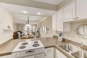 A kitchen with white cabinets, a double electric stove, and a sink.