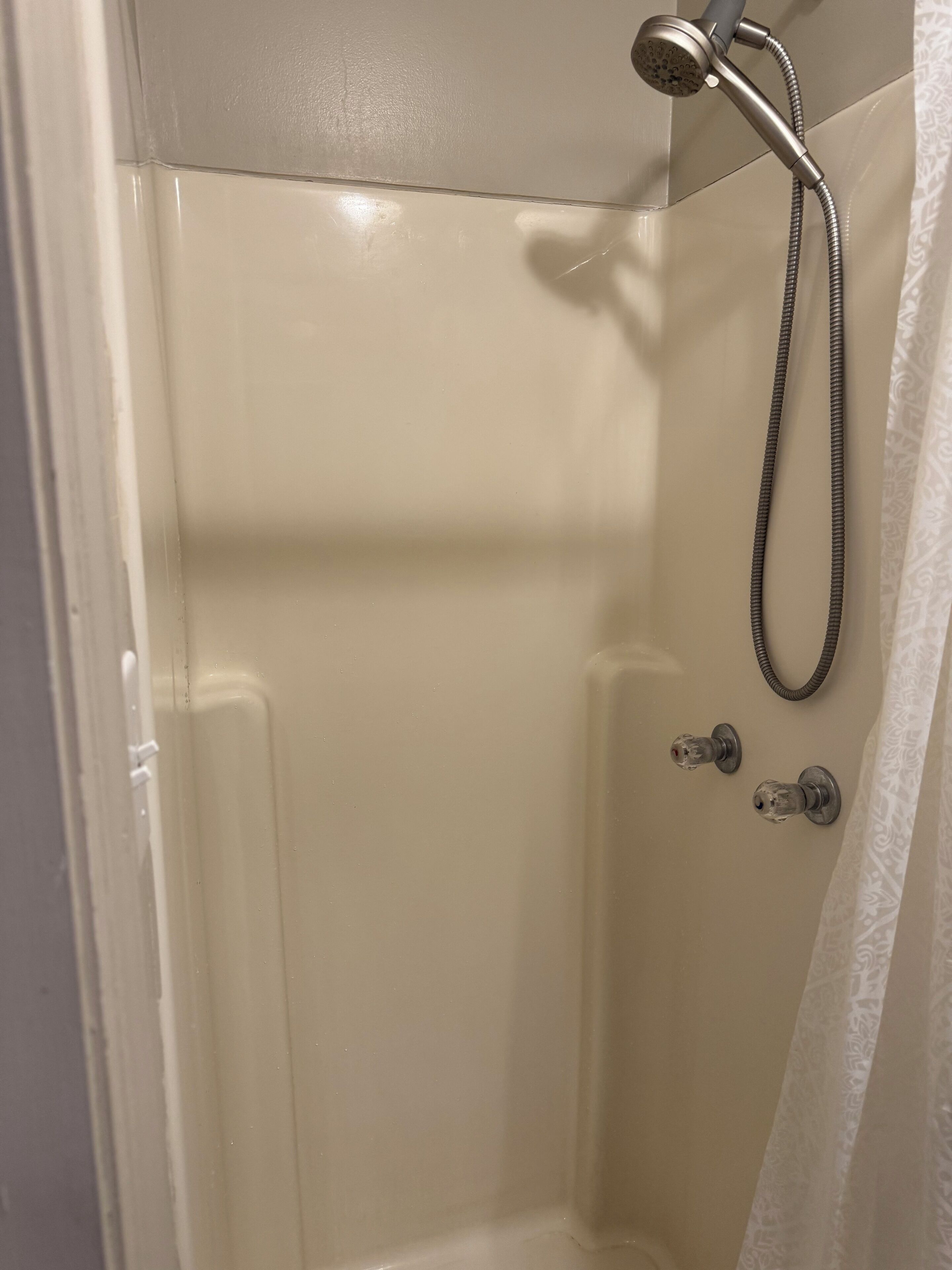 A shower with a handheld showerhead and a handheld shower attachment.