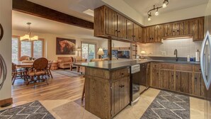 Una cocina amplia con armarios de madera, una isla central y un comedor con candelabro.