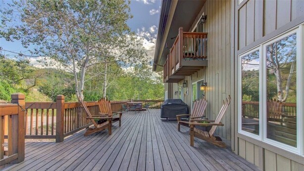 Una terraza de madera con mobiliario exterior y una parrilla.