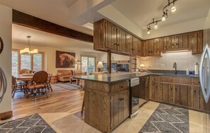 A spacious kitchen with wooden cabinets, a central island, and a dining area with a chandelier.