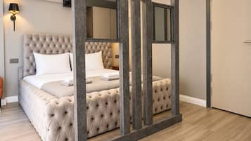 A bedroom with a tufted headboard, a bed with white linens, and a nightstand.