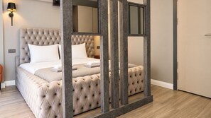 A bedroom with a tufted headboard, a bed with white linens, and a nightstand. - Talles City Hotel (Izmir)
