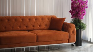 A sectional sofa with a tufted design, positioned against a white paneled wall.