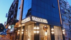 Um edifício de hotel moderno com uma placa de destaque para 'Talles City Hotel'.