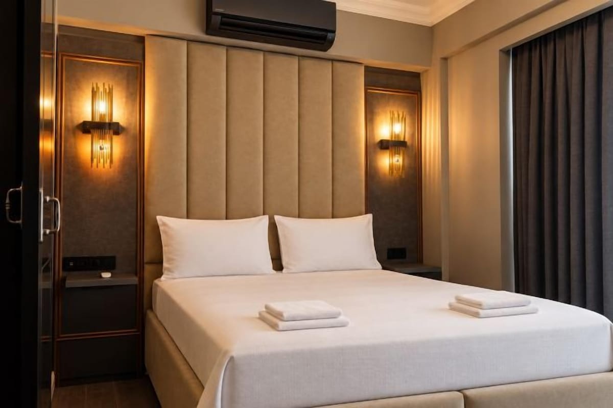 A hotel room with a large bed, two bedside tables, and wall-mounted lighting.