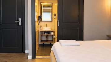 A hotel room with a bed, a bathroom with a sink, and a mirror.