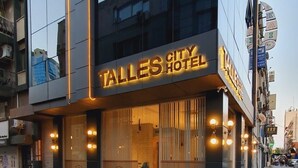Um hotel moderno com uma placa iluminada em destaque que diz 'TALLE'S CITY HOTEL'.