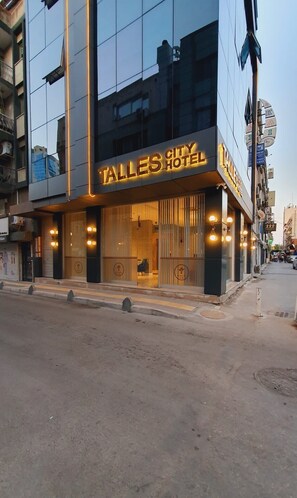 Um hotel moderno com uma placa iluminada em destaque que diz 'TALLE'S CITY HOTEL'.