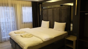 Et hotelværelse med en stor seng, et sengebord og udsigt gennem vinduet.