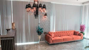 Un salon moderne avec un canapé capitonné, une sculpture équestre décorative, un lustre et un sol en marbre.