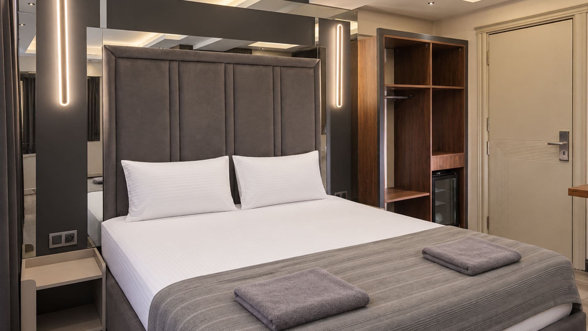 A modern bedroom with a large bed, a wardrobe, and a built-in closet.