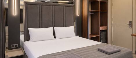 A modern bedroom with a large bed, a wardrobe, and a built-in closet.