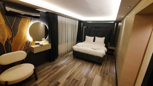 Une chambre d’hôtel moderne avec un grand lit, une table de chevet, une chaise et une coiffeuse avec un miroir.