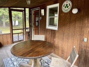 Un intérieur en bois avec une table ronde, une fenêtre et une porte donnant sur l’extérieur.