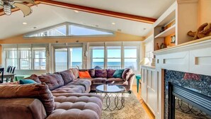 A spacious living area with a large sectional sofa, a fireplace, and a view of the ocean.