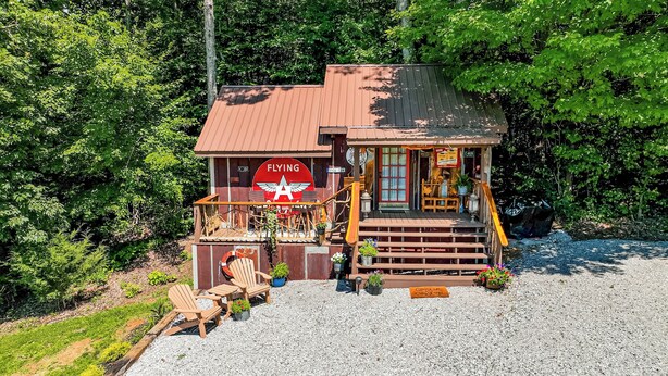A rustic wooden building with a red 'FLYING' sign, a porch with wooden chairs, and a gravel ground. - Fabulous Shack in the heart of Tellico Plains... (Tellico Plains)