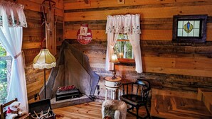 A rustic cabin interior with wooden walls, a fireplace, a small table with a lamp, and a dog. - Fabulous Shack in the heart of Tellico Plains... (Tellico Plains)