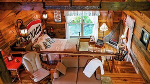 A cozy cabin interior with a bed, seating area, wooden walls, and a window with a view of greenery. - Fabulous Shack in the heart of Tellico Plains... (Tellico Plains)