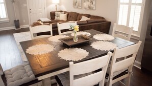 Un coin repas avec une table en bois, des chaises blanches et un vase rempli de fleurs.