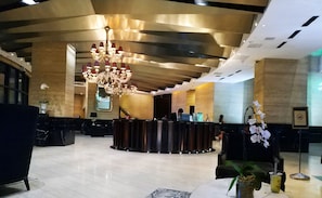 A lobby with a reception desk, a chandelier, and a large window. - The Gramercy Residences Makati Manila (Makati)