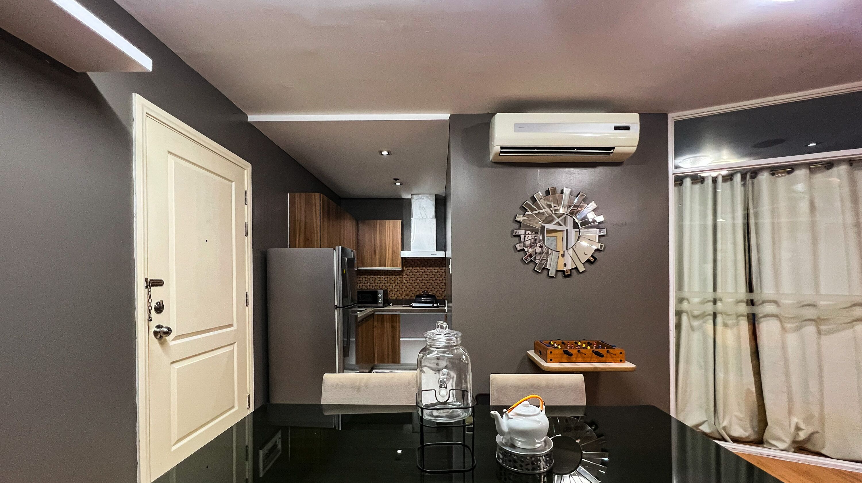 Een moderne keuken met een eethoek, met een glazen pot, een witte theepot en een decoratieve spiegel aan de muur.