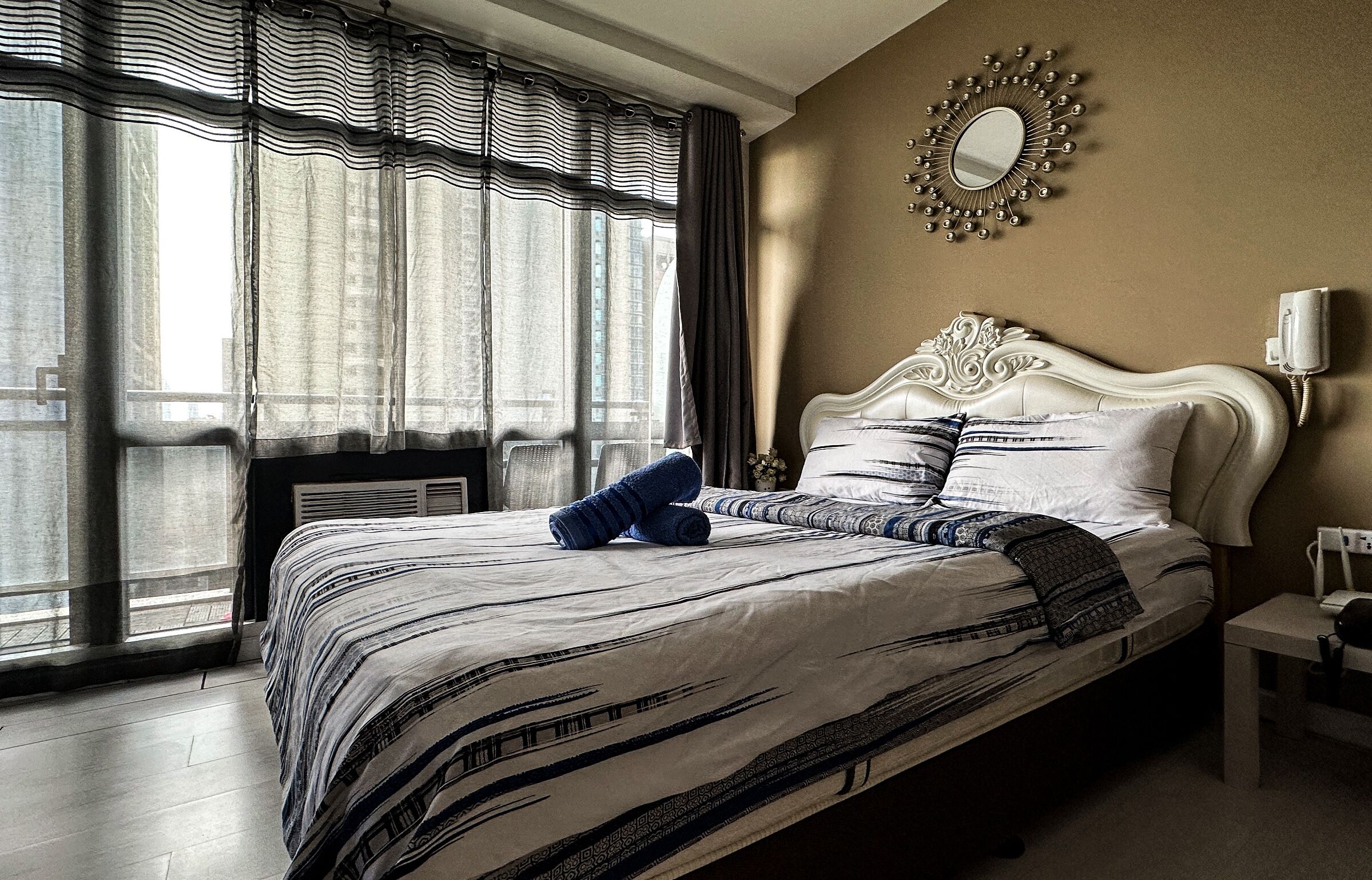 Een hotelkamer met een groot bed, een spiegel aan de muur en een raam met gordijnen.