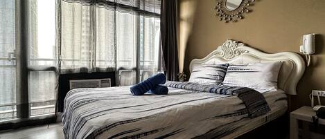 Een hotelkamer met een groot bed, een spiegel aan de muur en een raam met gordijnen.