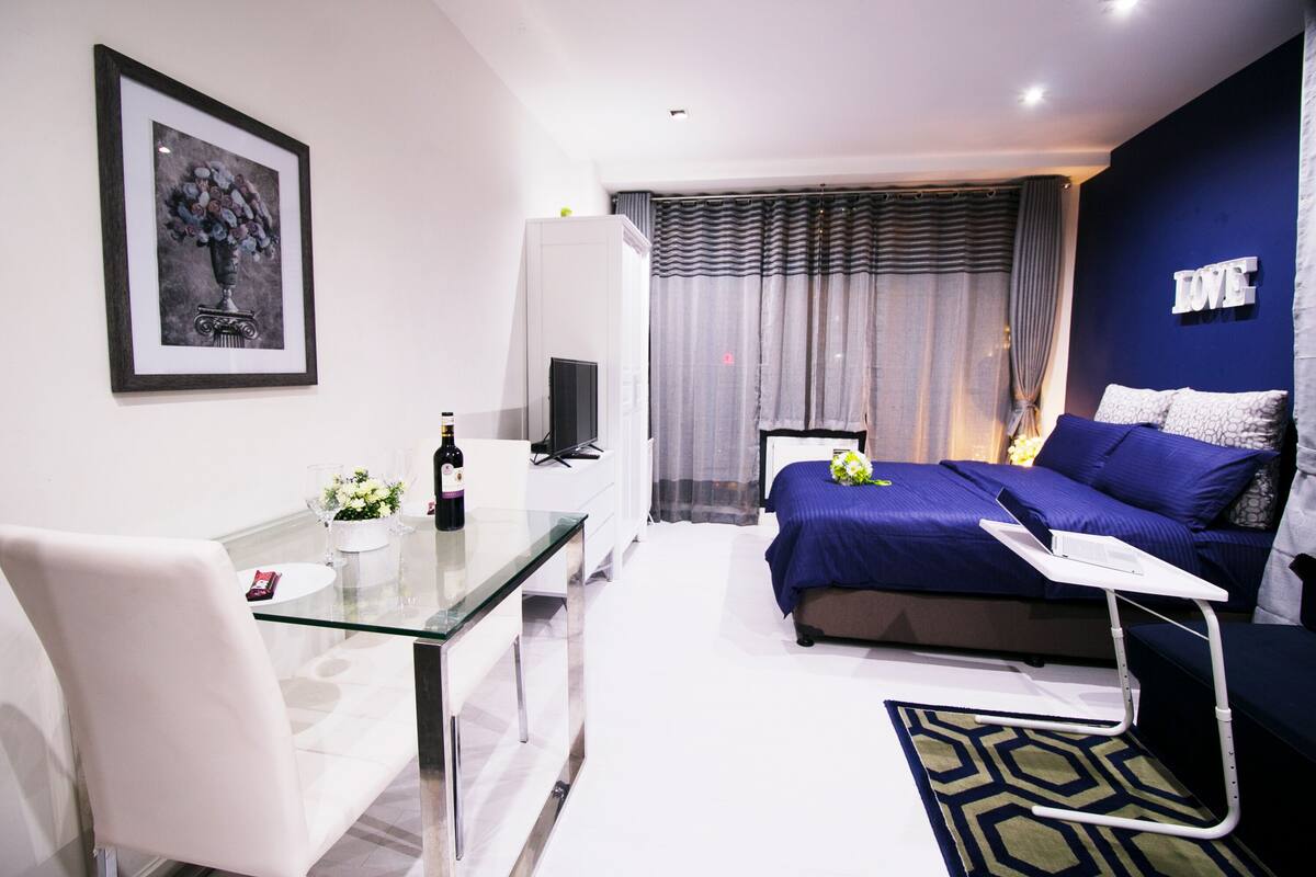 A modern bedroom with a bed, bedside table, and a desk with a chair.