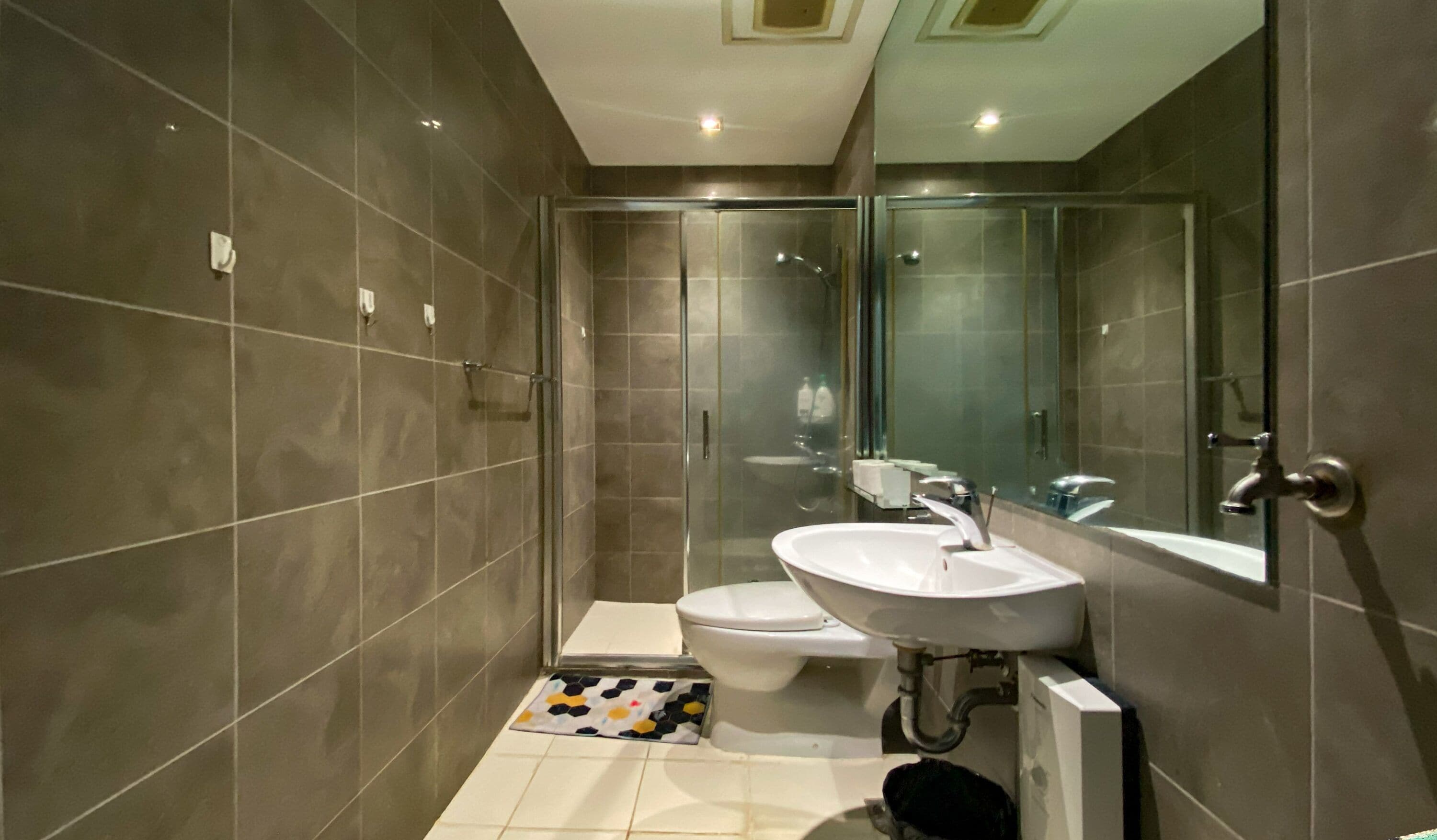 A modern bathroom with a glass shower enclosure, a white sink, and a toilet.