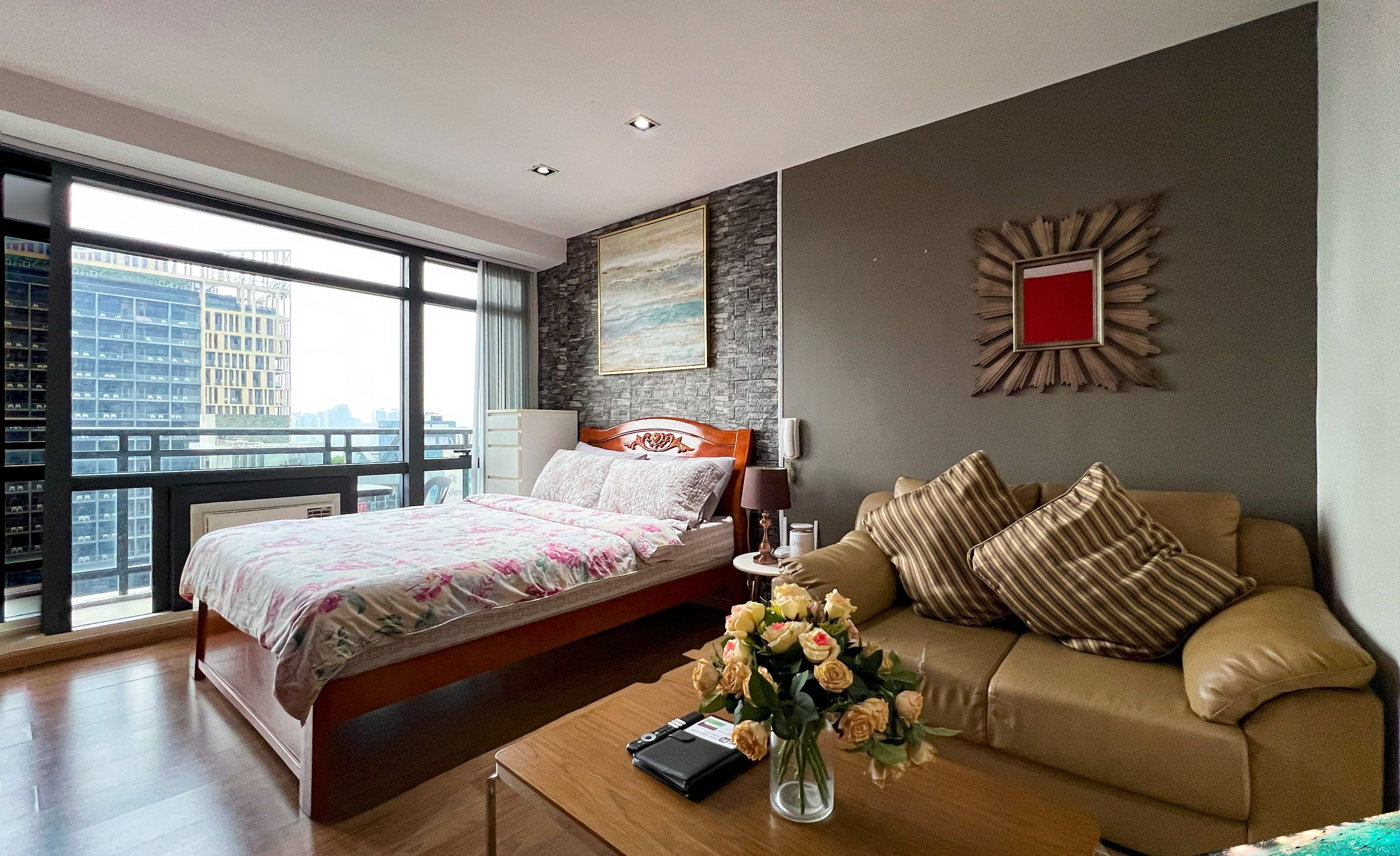 Een slaapkamer met een bed, een bank, een bijzettafeltje en uitzicht op de stad.