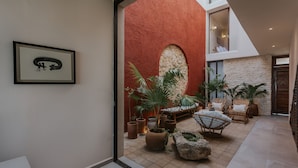 Un pati interior espaiós amb una paret vermella, un arc de pedra i plantes en testos.
