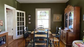 Une salle à manger avec une table et des chaises en bois, un ventilateur de plafond, un buffet en bois et une porte donnant sur l’extérieur.