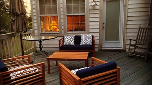 A wooden deck with outdoor furniture, including a sofa and chairs, and a table.